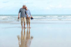 Smiling elderly Asian couple walking on a beach